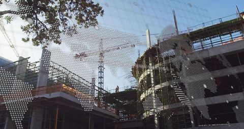 Construction worker inspecting building site with crane and blueprints
