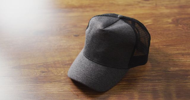 Black trucker hat resting on a wooden surface, ideal for illustrating casual fashion items, accessories, or lifestyle themes. Perfect for blogs, e-commerce sites, or marketing materials promoting casual apparel and accessories.