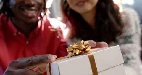 Joyful diverse couple gift wrapping for christmas celebration