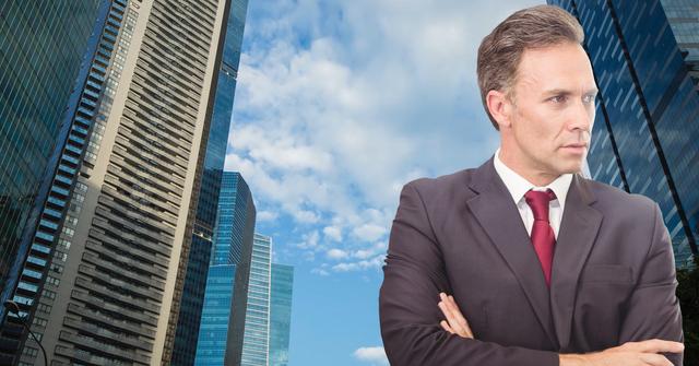 Digital composition of businessman standing with arms crossed against skyscraper in background