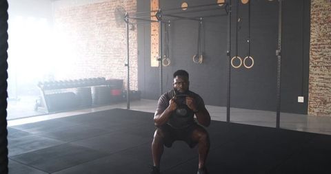Man Exercising with Kettlebell Goblet Squat in Gym