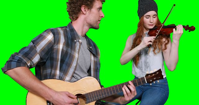 Man playing acoustic guitar while woman plays violin. Could be used for creative projects requiring background replacement, music-related content, or promotional work for musical duos.
