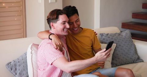 Joyful Multiracial Couple Video Calling at Home on Sofa