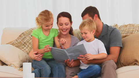 Happy Family Reading Book Together on Cozy Couch