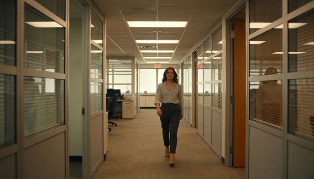 Confident businesswoman walking down office corridor past glass partitions and empty desks