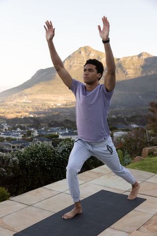 Man Practicing Yoga Lunge on Terrace with Mountain View