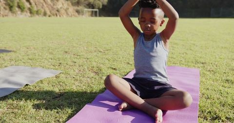 Peaceful Boy Meditating on Yoga Mat in Outdoor Sports Field