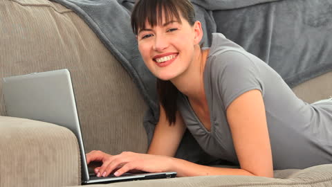Woman Relaxing on Sofa Using Laptop at Home
