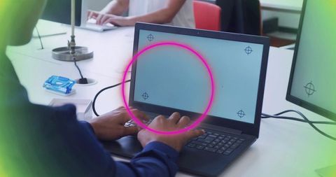 Hands typing on laptop with neon magenta circular overlay and mockup marks in coworking