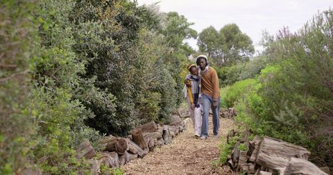 African american couple walking forest path wearing hats and scarf sharing quiet togetherness