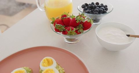 Healthy breakfast with berries, eggs, and juice on white counter