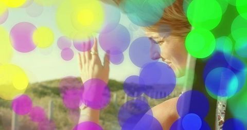 Contemplative woman enjoying sunlight with colorful bokeh overlays