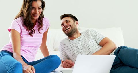 Happy Couple Using Laptop on Bed in Cozy Bedroom Setting