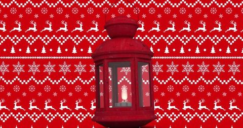 Red metal lantern with festive candlelight against holiday backdrop