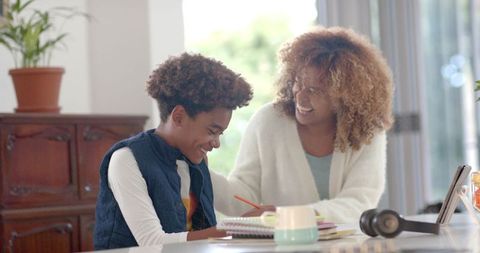 Smiling Mother Guiding Son with Homework in Cozy Kitchen Setting
