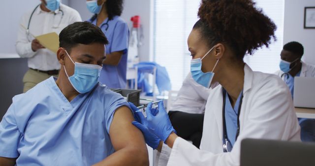 Nurse administering vaccine injection to patient wearing mask in healthcare facility. This image is ideal for use in educational materials, healthcare campaigns, informational brochures, and articles emphasizing the importance of immunization and public health safety.