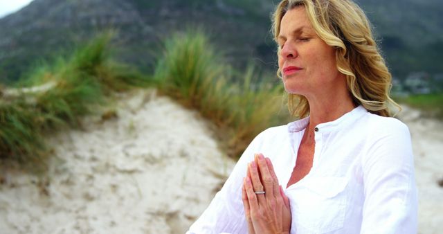 A middle-aged Caucasian woman practices meditation on a serene beach, with copy space - Download Free Stock Photos Pikwizard.com