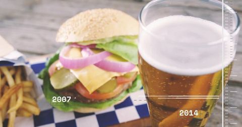 Gourmet cheeseburger sitting with fries and pint on weathered wooden patio table timeline