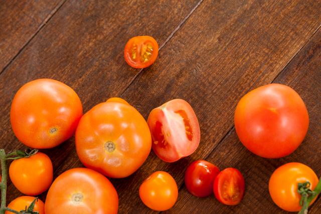 Close-up view of various types of fresh tomatoes on a wooden table. Perfect for illustrating concepts of healthy eating, organic produce, farm-to-table meals, and vegetarian or vegan diets. Ideal for food blogs, nutrition articles, and culinary websites.