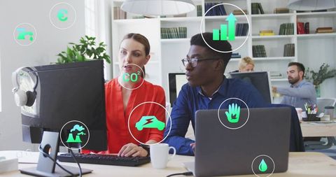 Colleagues collaborating on sustainable data dashboard with green eco infographic overlays