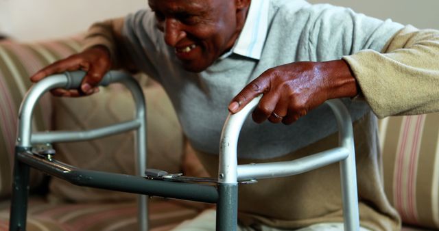 Elderly man is using a walker to assist with mobility while indoors. Creates an image of independence for older adults and showcases reality of daily life with assisted devices. Suitable for topics about healthcare, senior lifestyle, geriatric care, and promoting independence in the elderly population.