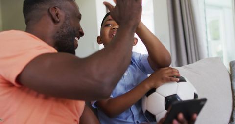 Father and Son Bonding with Soccer Ball at Home