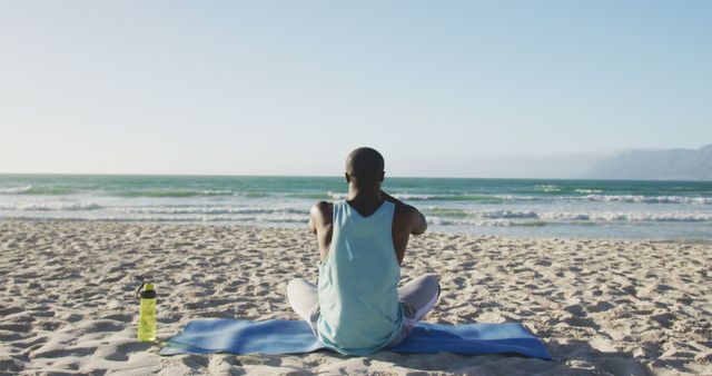 African american man practicing yoga on beach, exercising outdoors by the sea. fitness, healthy and active lifestyle concept.