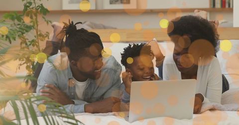 Family Bonding with Laptop on Bed Amid Glowing Lights