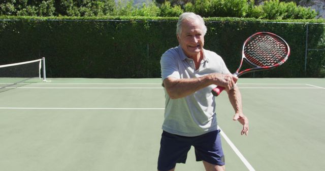 Senior man actively playing tennis on an outdoor court. Ideal for promoting active senior lifestyles, health and fitness, recreational sports, and outdoor physical activity. Useful for advertisements for senior fitness programs, sports equipment, and healthy living campaigns.