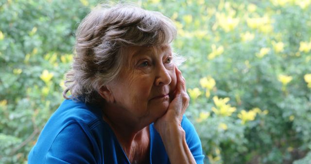 Older woman gazing thoughtfully in natural surroundings, ideal for illustrating senior lifestyle content, peaceful moments, and reflective states of mind. Useful in contexts of mindfulness, aging, and outdoor relaxation themes.