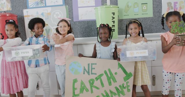 Children of various ethnic backgrounds are holding recycling bins and a sign that promotes eco-friendly practices. Ideal for educational materials, environmental campaigns, and diversity representation in school-related contexts.