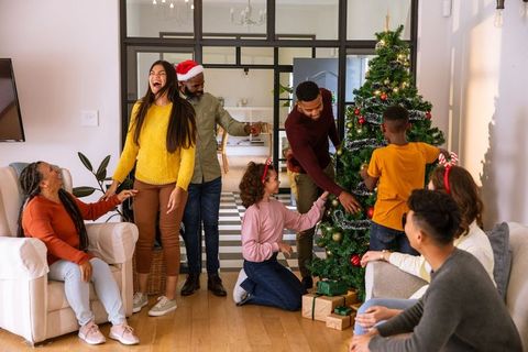 Family Decorating Christmas Tree in Warm and Cozy Living Room