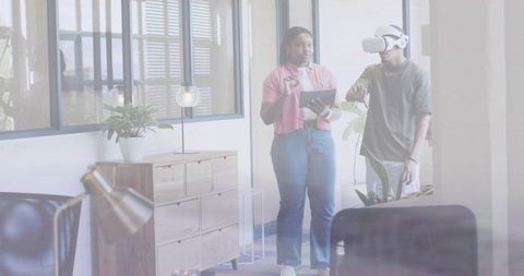 Virtual Reality Team Collaboration in Modern Office, Woman Guiding Colleague with Tablet