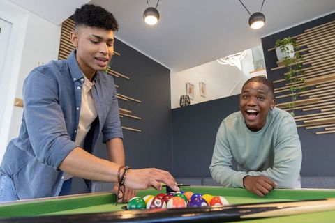 African american friends racking balls and laughing while playing pool in modern lounge