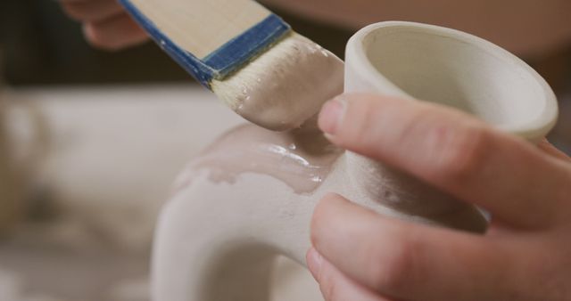 Close up view of female potter using glaze brush to paint on pot at pottery studio - Download Free Stock Photos Pikwizard.com