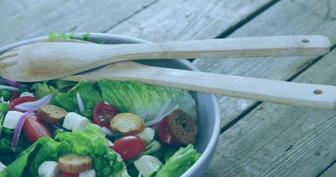 Rustic salad bowl with fresh vibrant ingredients and wooden servers