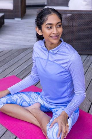 Young Woman Practicing Yoga on Outdoor Deck in Stylish Sportswear