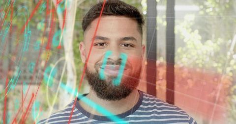 Bearded man standing behind holographic cyan-red grid overlay in sunlit garden window