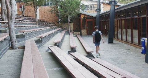 Schoolboy walking through campus courtyard with backpacks heading to classrooms