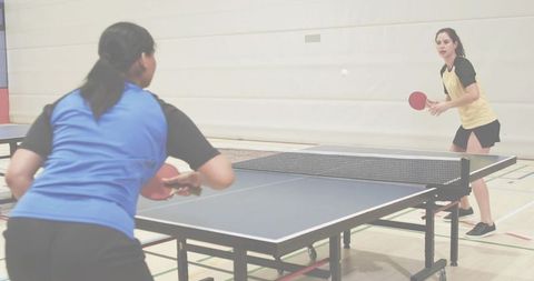 Female players playing table tennis in gym returning fast serve and reacting