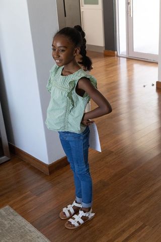Confident african american girl standing in sunlit entryway holding paper sheet