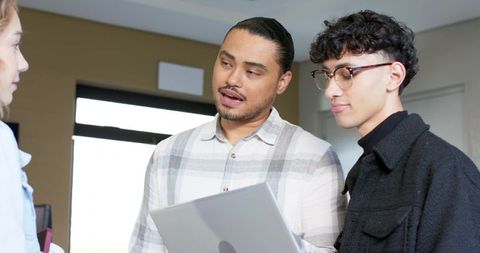 Two colleagues collaborating with laptop in modern meeting room, casual office teamwork