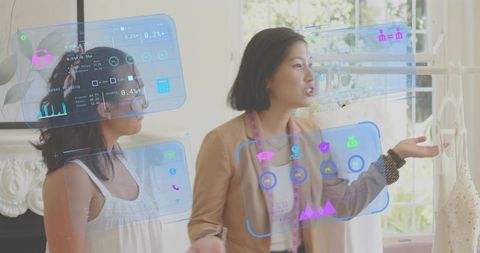 Asian fashion designer explaining AR data panels in boutique with measuring tape
