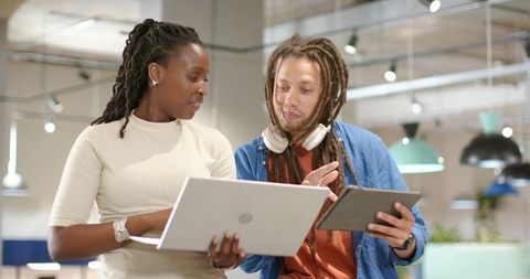 African American coworkers collaborating on laptop and tablet in modern coworking space