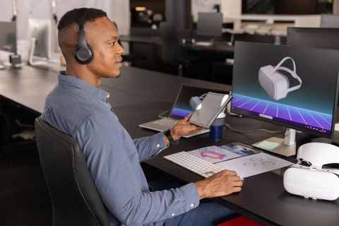 African American professional evaluating virtual reality headset at office using tablet
