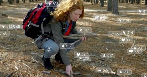 Redhead hiker gathering sticks in sunlit pine forest with floating social media icons