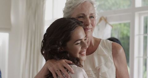 Bride Sharing Joyful Moment with Supportive Older Woman at Wedding Venue