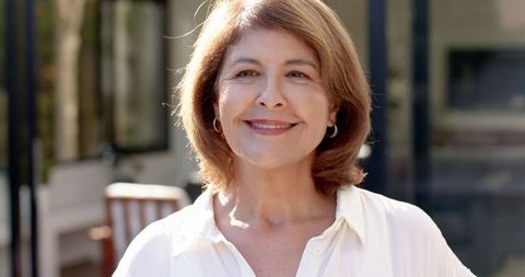 Happy Senior Woman Standing on Home Patio in Elegant Outfit