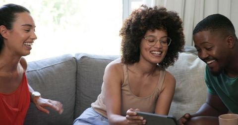 Diverse Friends Laughing and Sharing on Tablet in Living Room