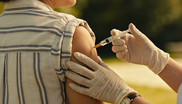 Nurse administering vaccine outdoors during community outreach clinic in sunlit park